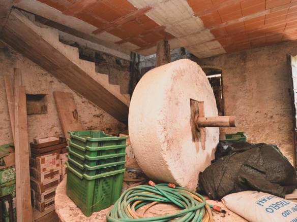 Notranji prostor za shranjevanje gradbenih materialov z zelenimi plastičnimi zaboji, lesenimi deskami, cevmi in velikim okroglim mešalnikom za cement na grobi steni.